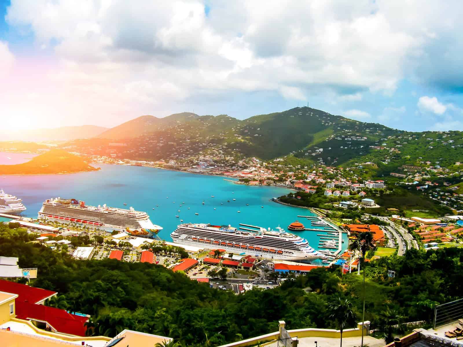 Overlooking a vibrant harbor with multiple cruise ships docked, surrounded by lush green hills and colorful buildings, one might wonder which cruise line is best to explore such breathtaking scenery.