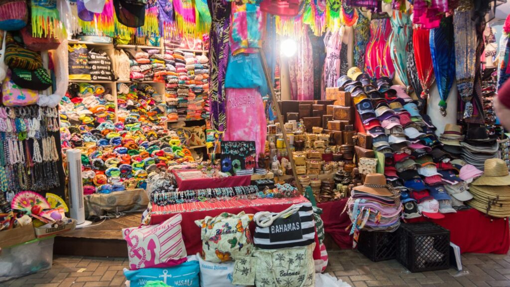 A vibrant market stall selling colorful clothing, hats, bags, and souvenirs with various items neatly displayed.