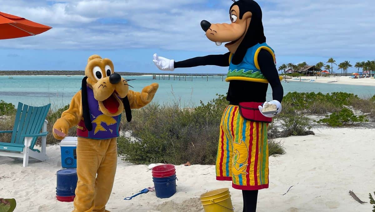 Pluto and Goofy in colorful beach attire, standing on a sandy beach with blue chairs and ocean in the background.