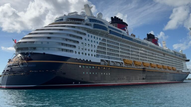 A large cruise ship docked at port under a clear blue sky.