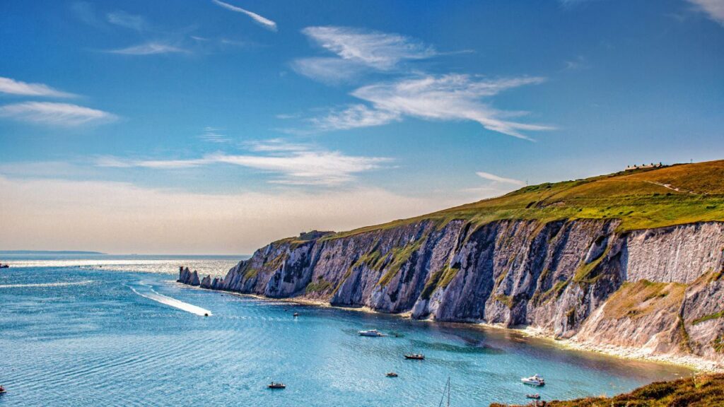 Scenic coastal view of a cliffside with boats on blue waters, under a clear sky.