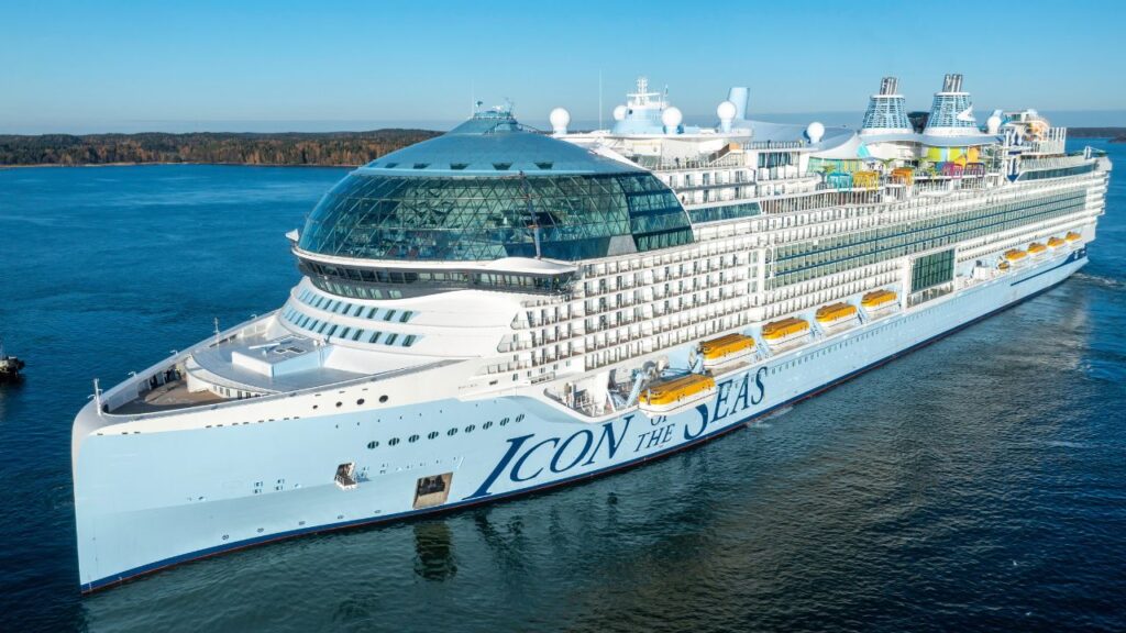 Large cruise ship "Icon of the Seas" sailing on a calm sea under a clear sky.