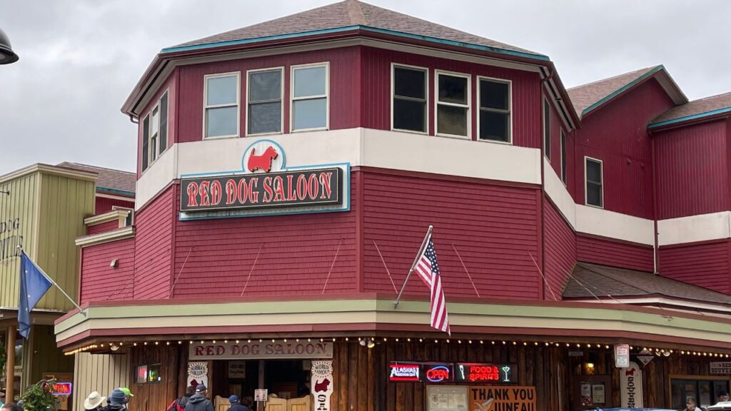 Red Dog Saloon with red siding, American flag, and neon signs in front of the building.