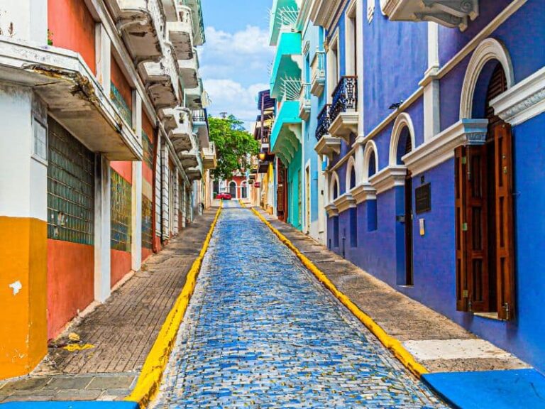 Colorful street with blue cobblestones and vibrant buildings in Old San Juan, Puerto Rico, under a clear sky.